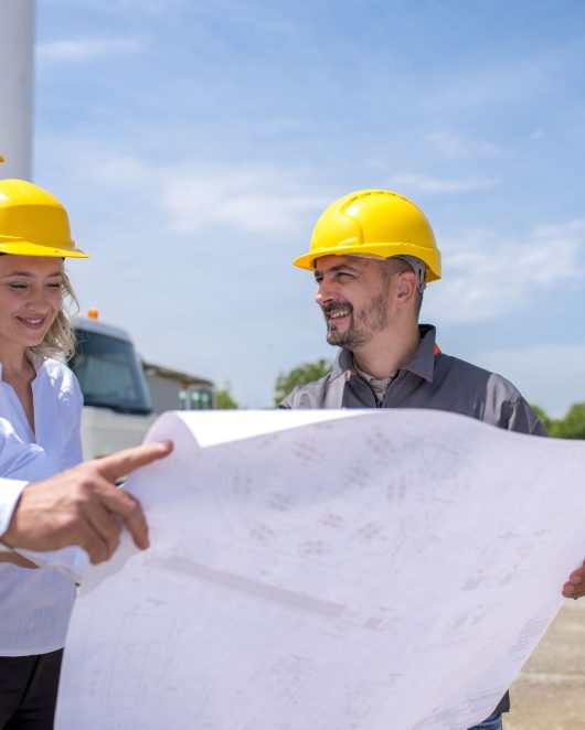 A group of construction workers looking at the plans and documents under the sunlight